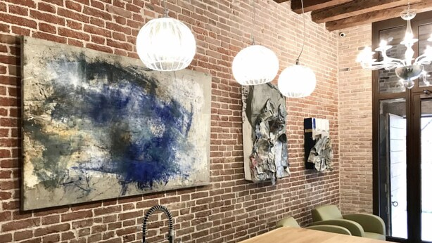 A dining area with a brick wall, abstract art, pendant lighting, and a wooden table. - At the Well of Light Suites Sandolo: double/single bedroom w/private bath. (Venezia)