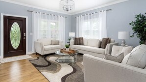 A living room with two sofas, a glass coffee table, a chandelier, and a door with a stained glass design. - Mountain Views, Hot Tub, Game Room | 20 min to Asheville! One Mile to Mars Hill University! (Mars Hill)