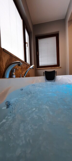 A bathroom with a bathtub, a window, and a shower area. - Arya Deluxe Apart (Kas)