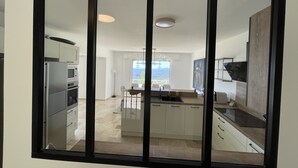 A modern kitchen with a central island, a dining area with a view, and a large window. - 5 bedroom villa with sea view in Tourettes (Tourrettes-sur-Loup)