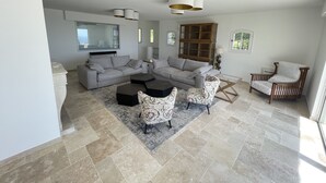 A modern living room with a sectional sofa, a coffee table, patterned chairs, a wooden cabinet, and a window with blinds. - 5 bedroom villa with sea view in Tourettes (Tourrettes-sur-Loup)