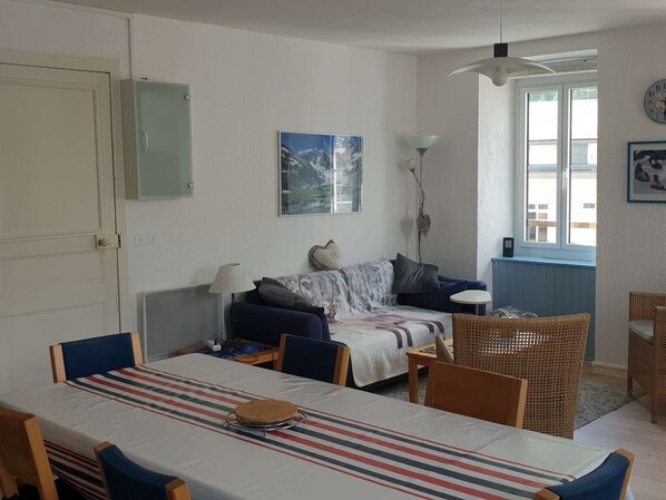 A cozy room with a dining table, chairs, a sofa, and a window. - Duplex for 6/7, city center, near cable car (Cauterets)
