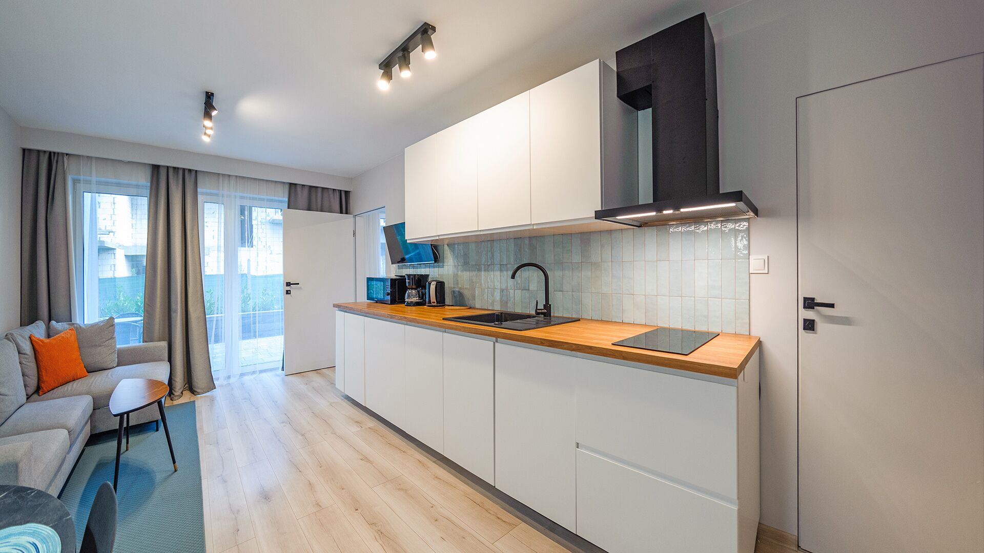 A modern kitchen with white cabinets, a wooden countertop, and a black faucet.