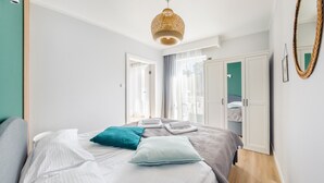 A bedroom with a bed, a wardrobe, and a hanging light fixture. - Apartamenty Sun & Snow Baltic Apartments (Pobierowo)