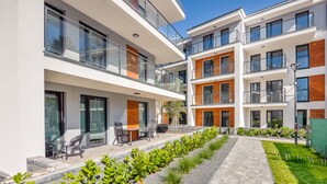 A modern apartment building with multiple balconies, outdoor seating, and a well-maintained garden area. - Apartamenty Sun & Snow Baltic Apartments (Pobierowo)