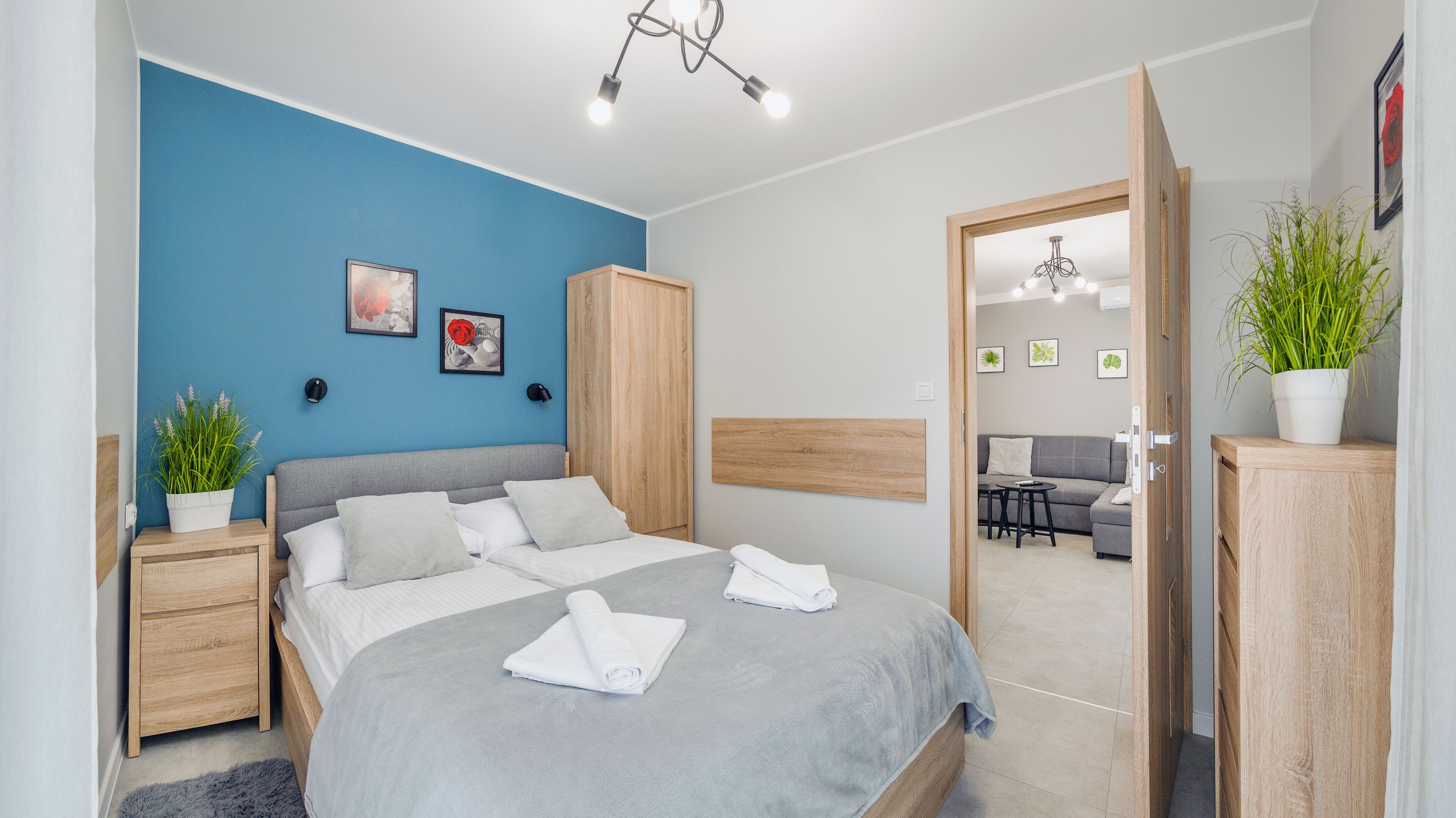 Une chambre moderne avec un lit, des tables de chevet, une armoire et une vue sur l’espace de vie.