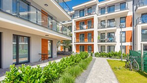A modern multi-story residential building with balconies, outdoor seating, and a well-maintained garden area. - Apartamenty Sun & Snow Baltic Apartments (Pobierowo)