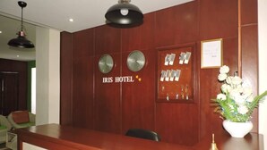 A reception desk with clocks, a framed certificate, and a vase of flowers. - IRIS HOTEL (Yaoundé)