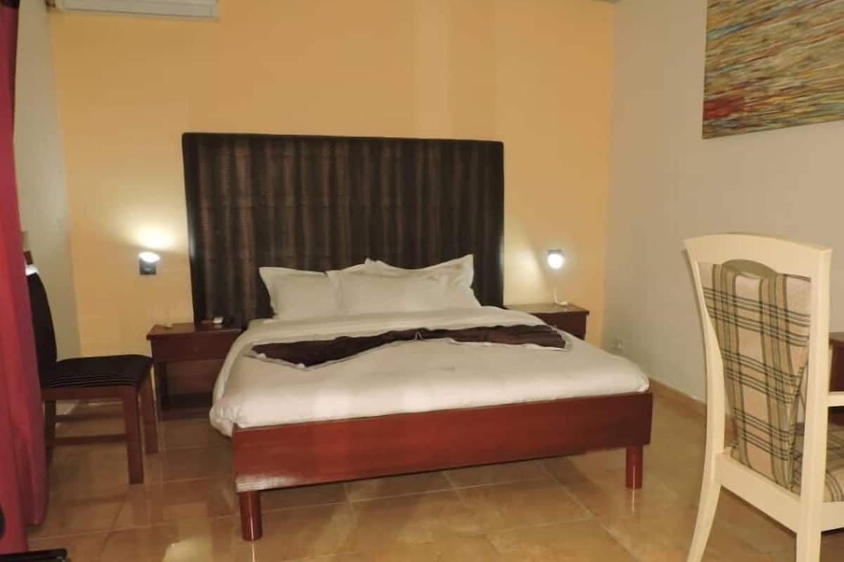 A hotel room with a bed, two bedside tables, a chair, and a wall-mounted artwork.