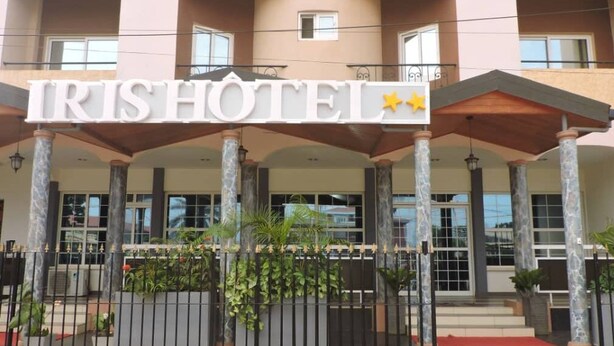 The exterior of the IRISHHOTEL with a prominent sign, a covered entrance, and a gated driveway. - IRIS HOTEL (Yaoundé)