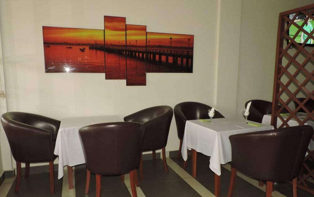 Un comedor con un cuadro de atardecer, cuatro sillas y una mesa.