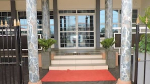 A hotel entrance with marble columns, a red carpet, and a glass door. - IRIS HOTEL (Yaoundé)