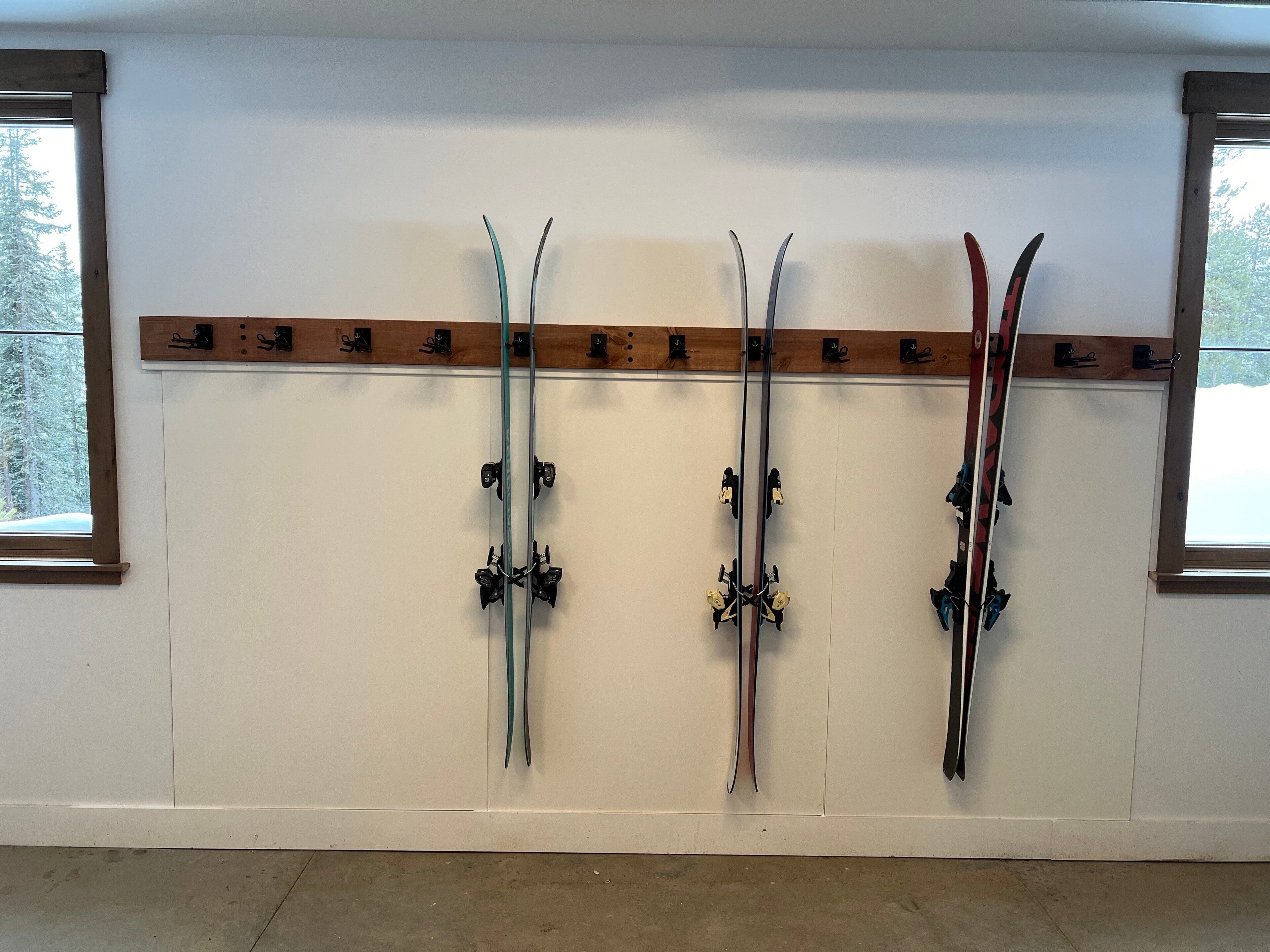 A wall-mounted ski rack with four pairs of skis.