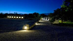 Une zone pavée, bordée de murs en pierre et d’une rangée de lampadaires.