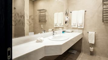 Un bagno moderno con un lavandino ampio, uno specchio, un porta asciugamani e un termosifone per asciugamani.
