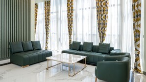 A modern living room with a green sofa set, a marble coffee table, and sheer curtains with geometric patterns. - Sphera by Stellar Hotels, Yerevan (Yerevan)