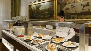 A buffet counter with various food items and a person serving. - Hotel Palacio Matutano Daudén (La Iglesuela del Cid)