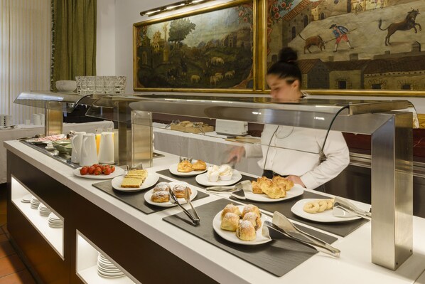 A buffet counter with various food items and a person serving. - Hotel Palacio Matutano Daudén (La Iglesuela del Cid)