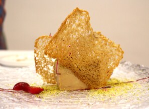 A dessert with a crispy, lattice-like structure on a plate with a decorative pattern. - Hotel Palacio Matutano Daudén (La Iglesuela del Cid)