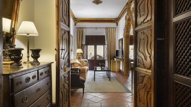 Un pasillo con puertas de madera decorativas, un sofá, una mesa de centro y un televisor en una habitación.