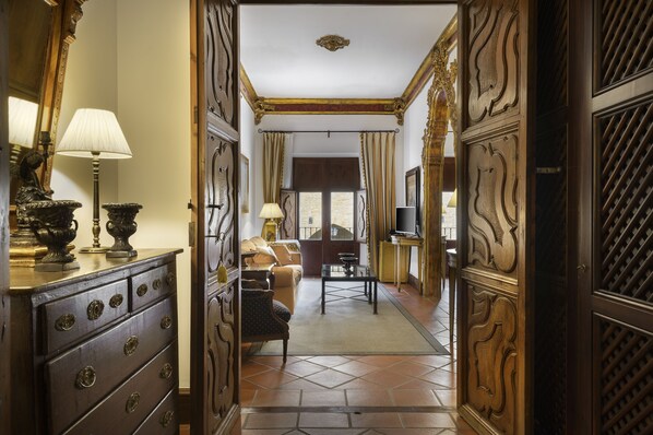 A hallway with ornate wooden doors, a sofa, a coffee table, and a television in a room. - Hotel Palacio Matutano Daudén (La Iglesuela del Cid)