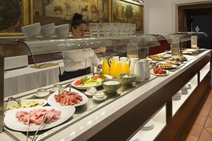 Un bufé con diversas opciones de comida y bebidas, incluyendo platos de carne, ensaladas y frutas.
