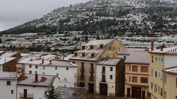 A town with buildings featuring red-tiled roofs and a prominent hill in the background. - Hotel Palacio Matutano Daudén (La Iglesuela del Cid)
