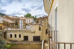 Un patio con edificios, un muro de piedra y una escalera.