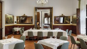 A formal dining room with a large round table set for a meal, surrounded by chairs. - Hotel Palacio Matutano Daudén (La Iglesuela del Cid)
