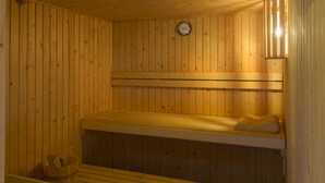 Una sauna con bancos de madera y un termómetro visible en la pared.