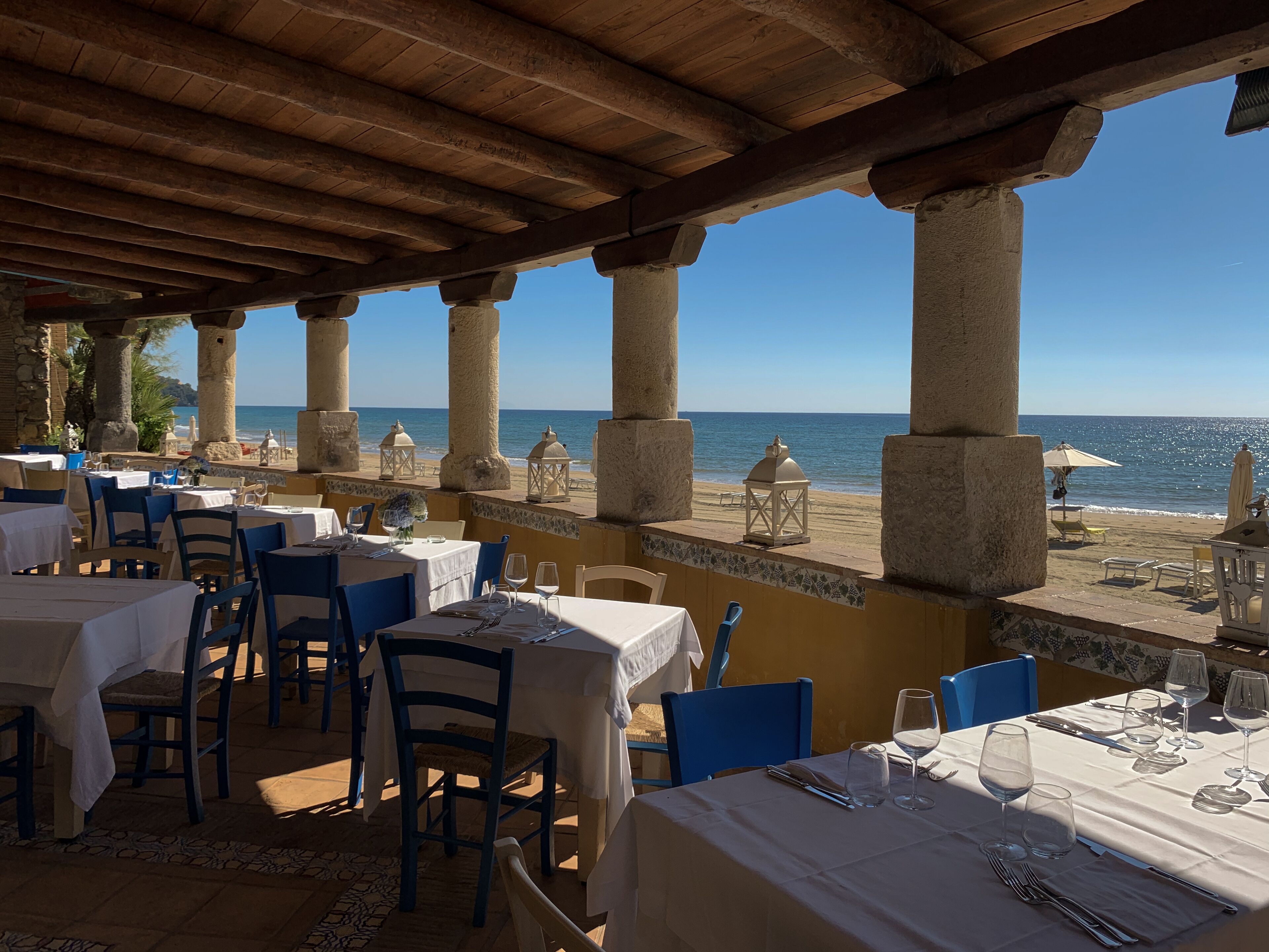 A seaside restaurant with tables set for dining, overlooking the ocean.