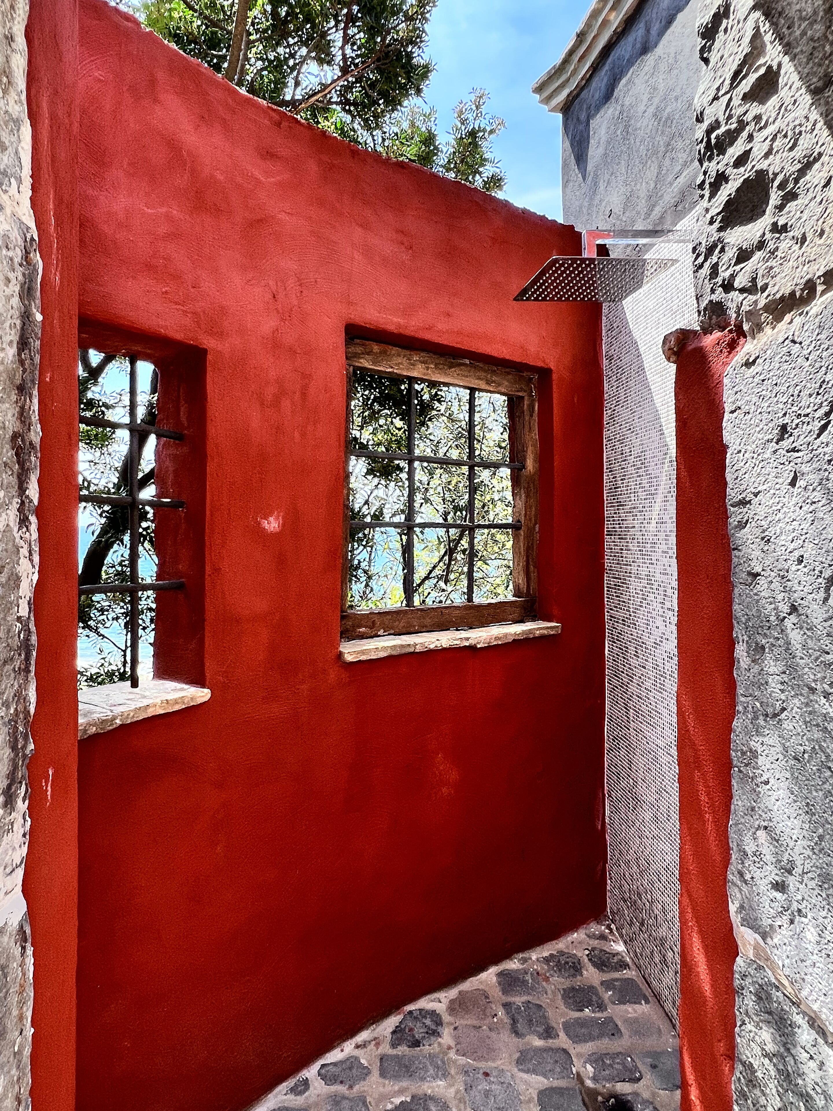 A narrow corridor with red walls and two windows, one with a metal grid.