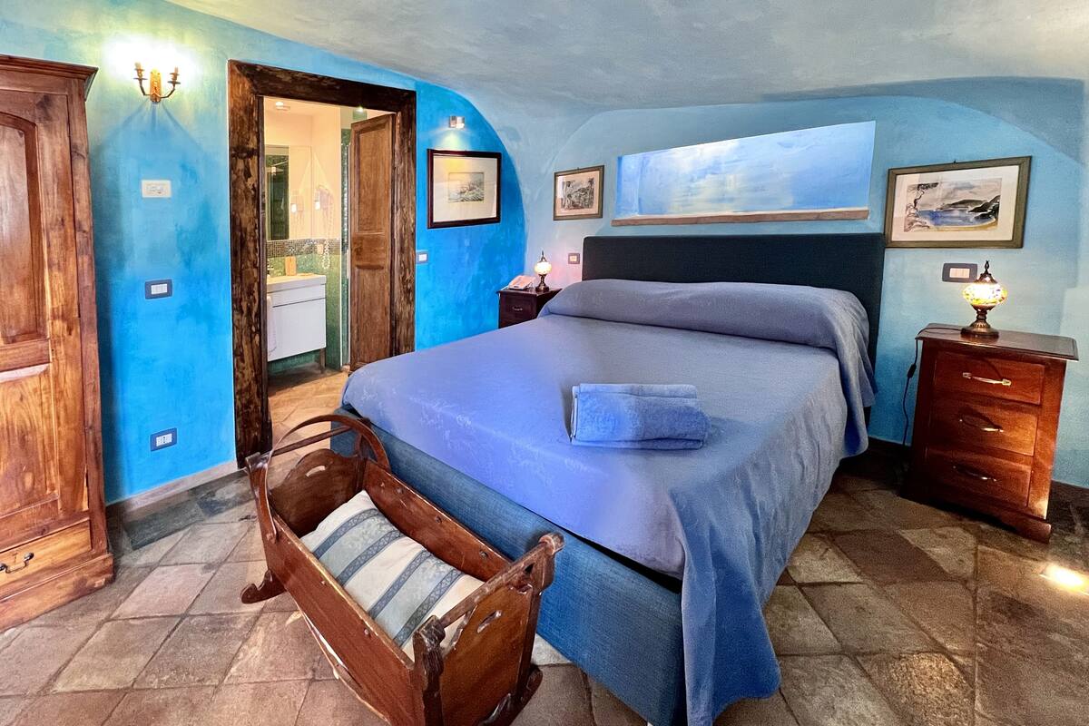 A bedroom with a bed, wooden furniture, and a blue wall.