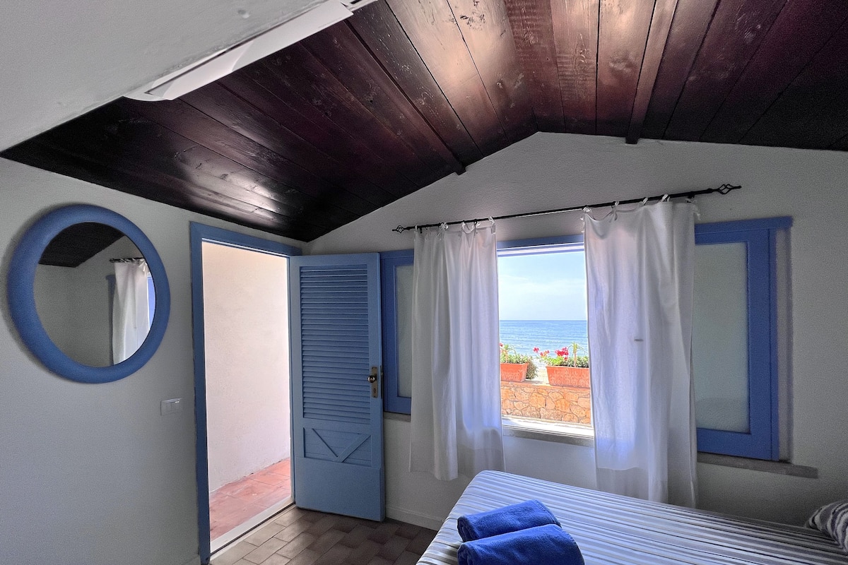 A bedroom with a bed, a window with curtains, a door, and a mirror.