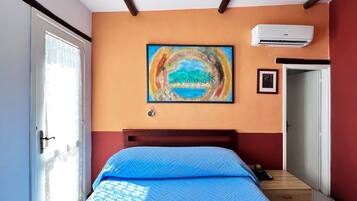 Une chambre à coucher avec un lit, un tableau, un appareil de climatisation et une porte.