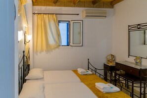 Een slaapkamer met een bed, een bureau, een stoel, een spiegel en een raam met gordijnen.
