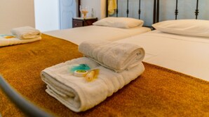 Une chambre d’hôtel avec deux lits, chacun étant équipé de draps et d’oreillers blancs. On trouve des serviettes sur les lits, ainsi qu’une petite table avec une lampe et une bouteille.