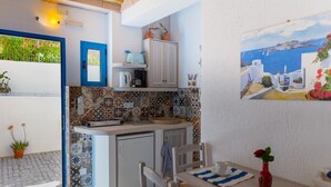 Une cuisine compacte avec des carreaux décorés, un petit réfrigérateur et un coin repas agrémenté de sets de table à rayures.