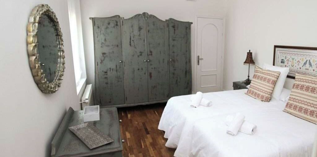 Une chambre à coucher avec un lit, une armoire, un miroir et une table de chevet.