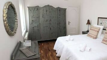 Une chambre à coucher avec un lit, une armoire, un miroir et une table de chevet.