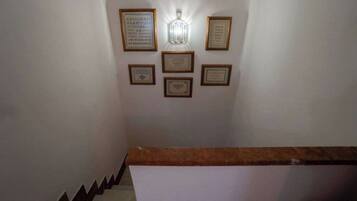Escadaria com corrimão de madeira e parede exibindo vários certificados ou placas emolduradas.