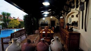 A poolside area with a wooden table and chairs, surrounded by large vases. - THE VILLAR HOUSE (Estación de Brazatortas-Veredas)