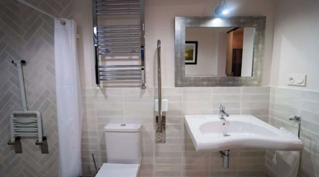 A bathroom with a white sink, a mirror, a towel rack, and a toilet.