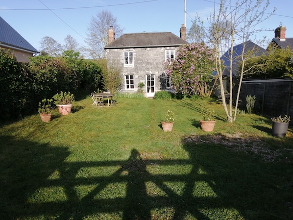A house with a well-maintained lawn, a wooden table, and potted plants.