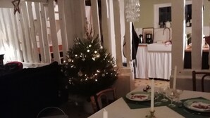 A dining area with a Christmas tree, candle-lit tables, and hanging crystal chandeliers.