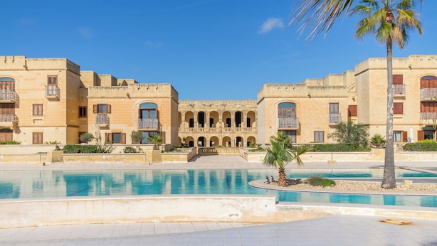 A large building with multiple balconies and a central courtyard with a swimming pool. - Harbour Views Gozitan Villa + Shared Pool (Ghajnsielem)
