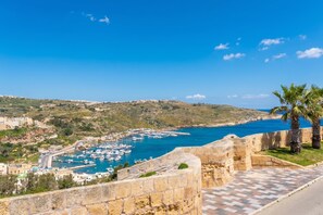 A coastal town with a marina, stone walls, and a clear blue sky.