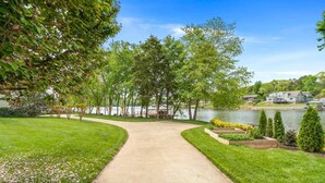 A well-maintained pathway leading to a lakeside property with a view of a house and dock.