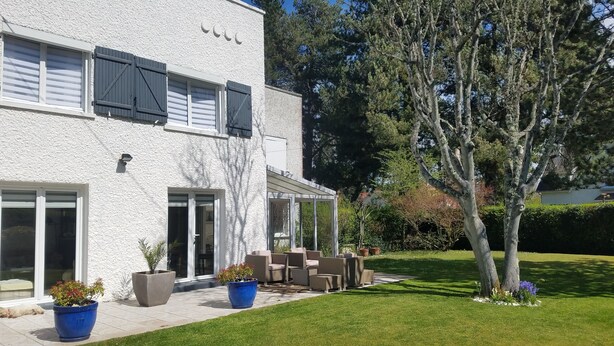 Une maison à deux étages dotée d’un patio, de meubles d’extérieur et de plantes en pot.