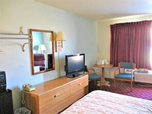 A hotel room with a bed, a television, a desk with a telephone, a chair, and a mirror. - Marifah Inn (Williamsburg)